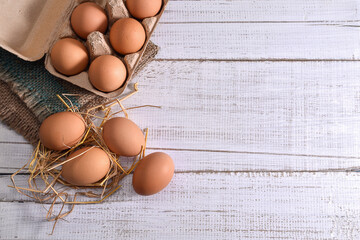 Chicken eggs in cardboard rack or egg box on white table. Top view.