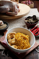 Mie Ayam Yamin or Yamin chicken noodles are served in a bowl placed on a saucer, decorated with beef on a wooden table. Top View.