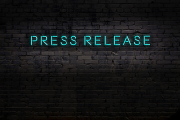 Night view of neon sign on brick wall with inscription press release