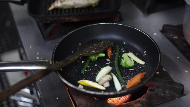 Cooking red sauce, with sauteed vegetables, caramelised onions, red chillies and capsicum on a hot oil pan.
