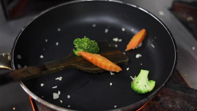 Cooking red sauce, with sauteed vegetables, caramelised onions, red chillies and capsicum on a hot oil pan.