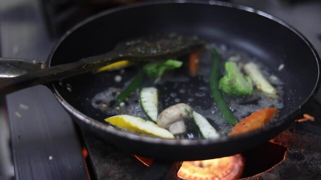 Cooking red sauce, with sauteed vegetables, caramelised onions, red chillies and capsicum on a hot oil pan.