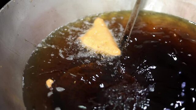 Making indian style fritters or bread pakoda by deep frying vegetables stuffed marinated bread in hot oil kadhai.