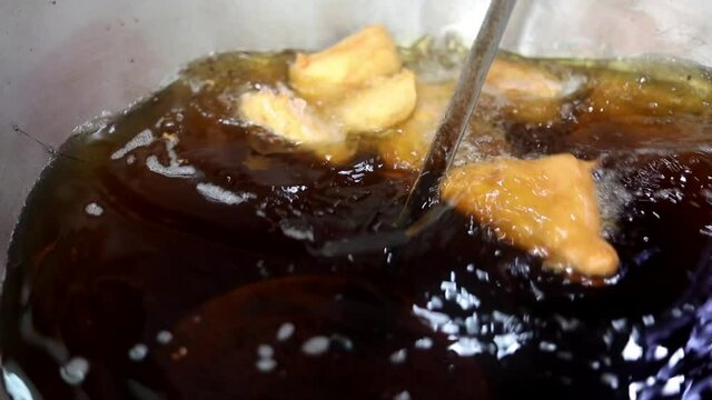 Making indian style fritters or bread pakoda by deep frying vegetables stuffed marinated bread in hot oil kadhai.