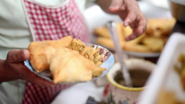 Making indian style fritters or bread pakoda by deep frying vegetables stuffed marinated bread in hot oil kadhai.