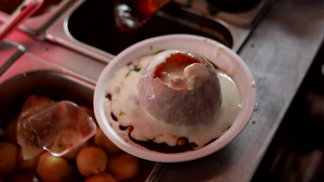 Making indian style street chaat and raj kachori with topped spices, red sauce and corns. 