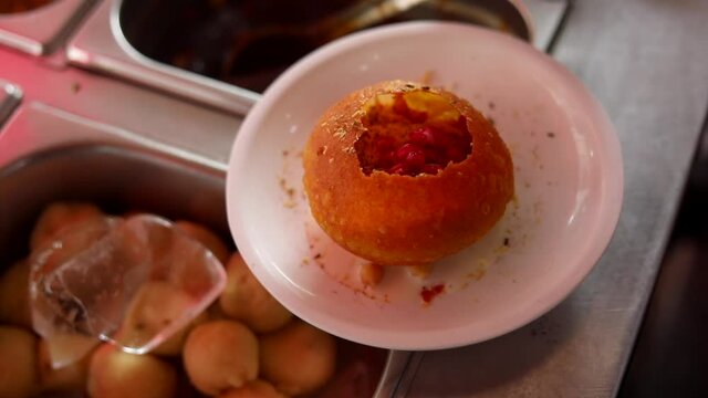 Making indian style street chaat and raj kachori with topped spices, red sauce and corns. 