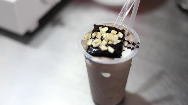 Making ice cream sundae shake dessert with cream, fruits and cherry toppings.