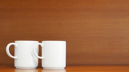 Two stacking white porcelain mugs on wooden shelf in the kitchen room at home Living and lifestyle concept