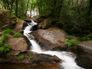 River Leça Waterfalls in Monte Cordova, Portugal. The river water runs down the big rocks of the mountain, under the green canopy of the trees in the spring