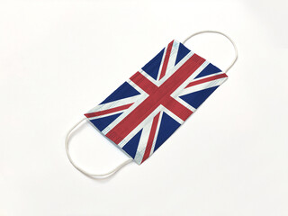 Concept. Disposable medical surgical face mask with United Kingdom UK country flag superimposed on it, on white background. Protection against Covid-19 virus; coronavirus outbreak.
