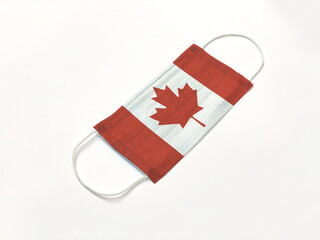 Concept. Disposable medical surgical face mask with Canada country flag superimposed on it, on white background. Protection against Covid-19 virus; coronavirus outbreak.