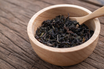 Chinese leaf tea in a wood bowl on grained wood background