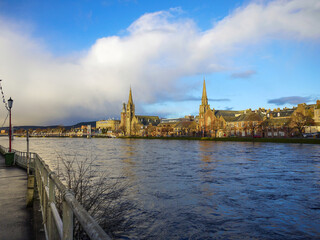 View of historical buildings in Inverness bathing in late afternoon sunshine across the River Ness.