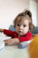 Fototapeta premium Bebe sentada na cadeira próxima a mesa e brincando com um caderno universitário