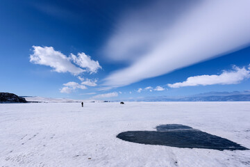 Frozen Lake Baikal covered with snow and cleared of snow in shape of heart. Beautiful stratus clouds over the ice surface on a frosty day.