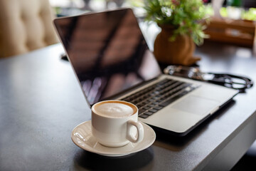 Coffee placed on the desk beside the computer, laptop and Earpiece