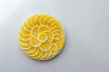 Lemon cut into slices on a white plate. Juicy round pieces of yellow lemon. Citrus is a source of vitamin and ascorbic acid.