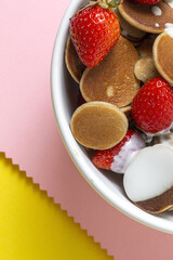 Homemade cereals mini pancake with yogurt, honey and strawberries on colorful background.