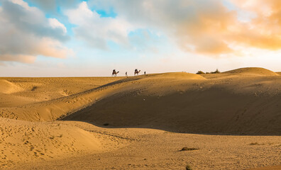 Fototapeta na wymiar Sand dunes of Thar desert Jaisalmer with view of tourist enjoying camel safari at Rajasthan India