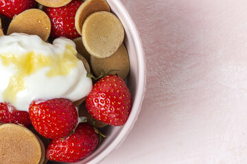 Homemade cereals mini pancake with yogurt, honey and strawberries on colorful background.