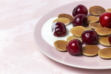 Homemade cereals mini pancake with yogurt, honey and strawberries on colorful background.