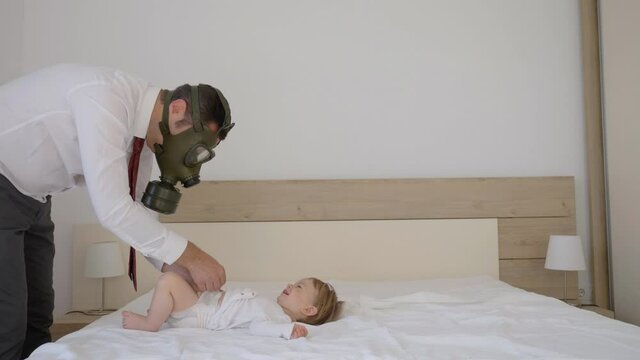 Businessman with gas mask changing baby child diaper, work from home, elegant man with shirt and tie, gender equality, parental role