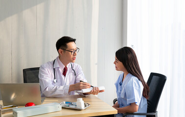 Doctor with female patient. Doctor and patient discussing something while sitting at the table, explaining diagnosis to his female patient. Medicine and healthcare concept. Coronavirus, Covid-19.