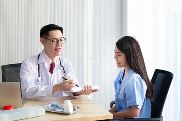 Doctor with female patient. Doctor and patient discussing something while sitting at the table, explaining diagnosis to his female patient. Medicine and healthcare concept. Coronavirus, Covid-19.