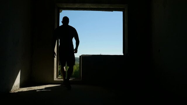 Muscular athlete running up stairway. Powerful sportsman running up dark staircase behind doorway during fitness workout inside abandoned building site