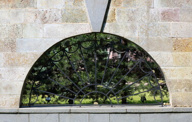 A semicircular window in the stone-tiled wall was covered with a metal grating