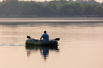 A man floats in a boat on the lake