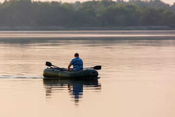 Foto op Canvas A man floats in a boat on the lake © schankz