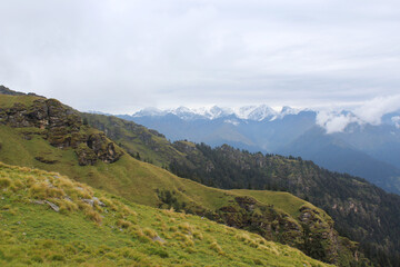 a green valley and snow peaked mountains.