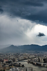 airplane flying into raining cloud over the city