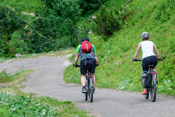 Obraz premium Zwei Radfahrer mit einem E-Bike bei einer Abfahrt im Gerbirge