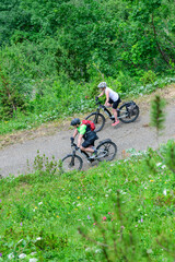 Zwei Radfahrer mit einem E-Bike bei einer Abfahrt im Gerbirge