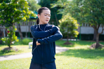 Portrait of Asian woman wearing earphones listening to music was sick with body pain at park.