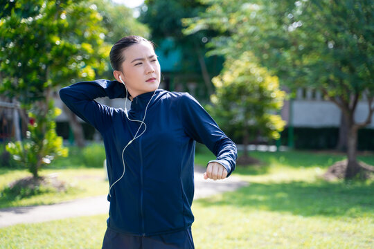 Portrait of Asian woman wearing earphones listening to music was sick with body pain at park.