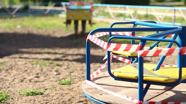 empty playground in the park during the quarantine with red ribbons