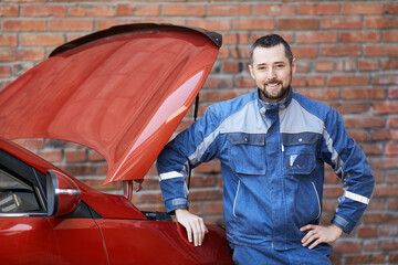 Car service worker near the car. Car service worker smiles at the camera.