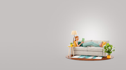 Young pretty female reads book lying on a couch at her home.