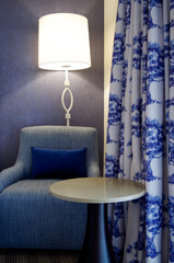 Comfortable grey armchair or coucher with blue pillow against purple wallpaper inside luxury...