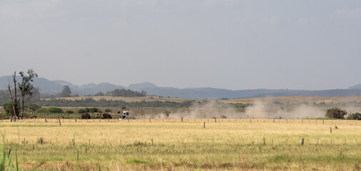 Fototapeta na wymiar Dirt road cutting through the rural landscape in an agricultural production field