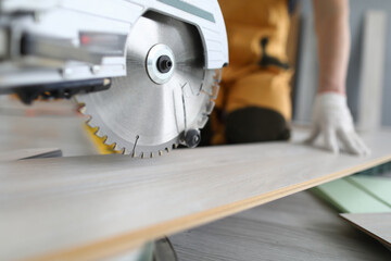 Close-up of professional craftsman working with metal electrical equipment. Man in protective white gloves and yellow uniform for work. Detailed picture. Renovation and construction site concept