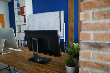 Close-up of modern office interior with computer and wall board for writing ideas. Creative space for people. Red brick walls. Business agency and career growth concept