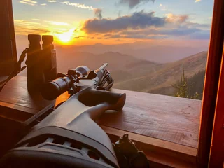 Stoff pro Meter Close up of rifle and binocular for  hunting. View from the window on sunrise. © Michal