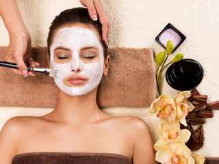 Woman having a facial cosmetic mask at spa salon.