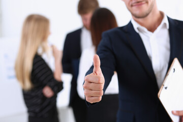 Handsome smiling man showing OK or approval sign with thumb up in creative people office portrait. High level and quality service, job offer, excellent education, advisor, serious business concept