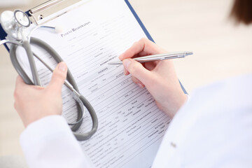 Female doctor hand hold silver pen filling patient list at clipboard pad closeup. Physical, exam, er, disease prevention, ward round, visit check, 911, prescribe remedy, healthy lifestyle concept